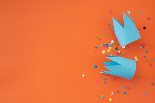Free Vibrant paper crowns with colorful confetti on an orange surface, ideal for festive themes. Stock Photo