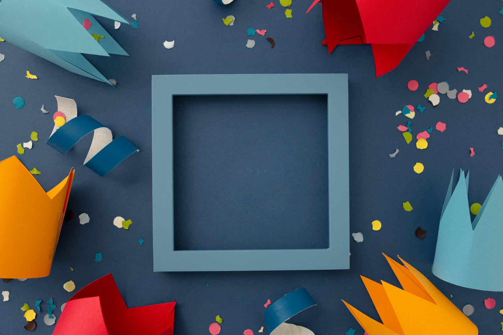 Paper party hats and confetti on deep blue — photo by Daniel Enamorado on Pexels