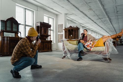 Free A photographer captures a styled photoshoot with models in a vintage furniture store. Stock Photo