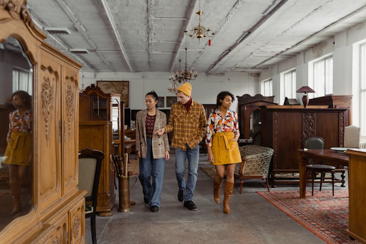 A Group Of People Walking On The Aisle Between Wooden Furniture