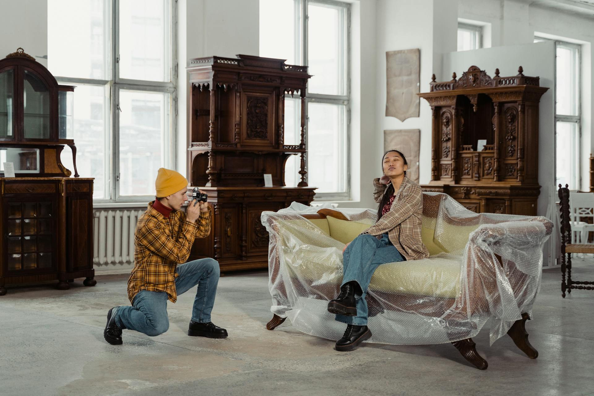 Woman posing for a photo on a sofa covered in bubble wrap in an antique furniture exhibit.
