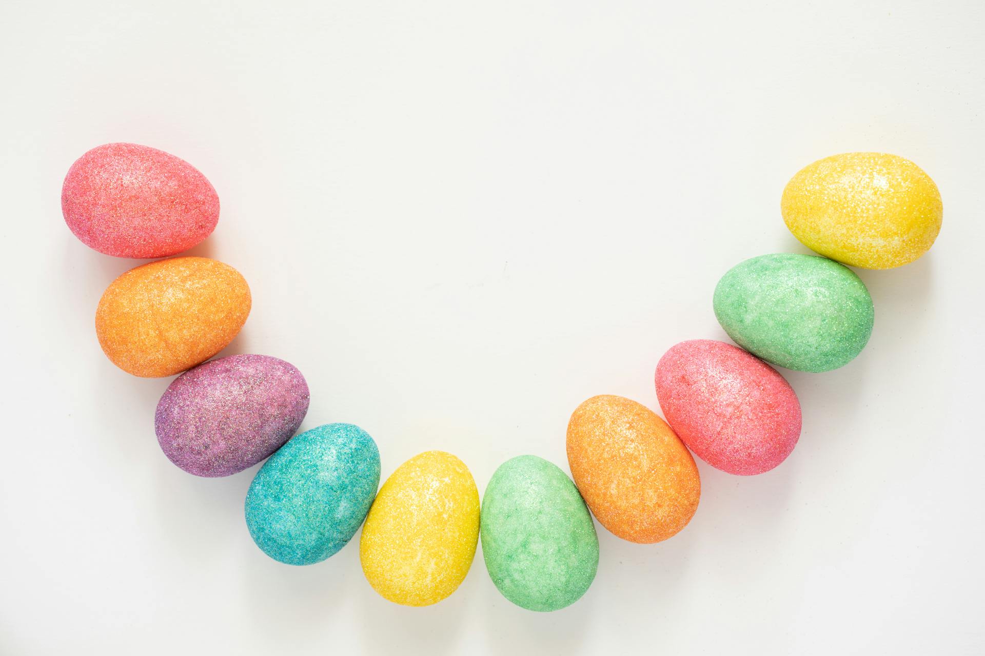 Vibrant arrangement of colorful Easter eggs in a half-circle pattern on a white background.