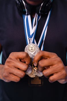 Close-up of hands holding a silver medal showcasing achievement and recognition.