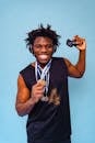 Man with Dreadlocks Posing with Gold Medals on Blue Background
