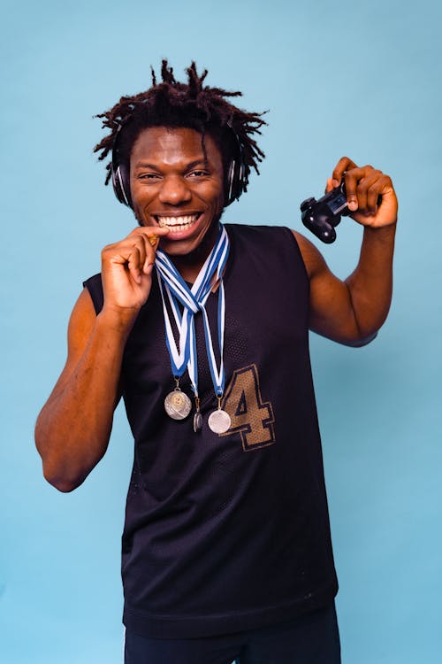 Man with Dreadlocks Posing with Medals on Blue Background