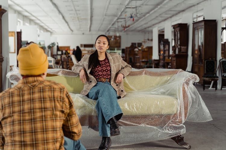 A Woman In A Stylish Outfit Sitting On An An Antique Sofa