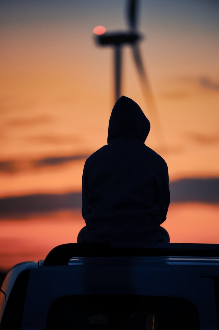 Silhouette Of Person Sitting On A Car Roof  During Sunset