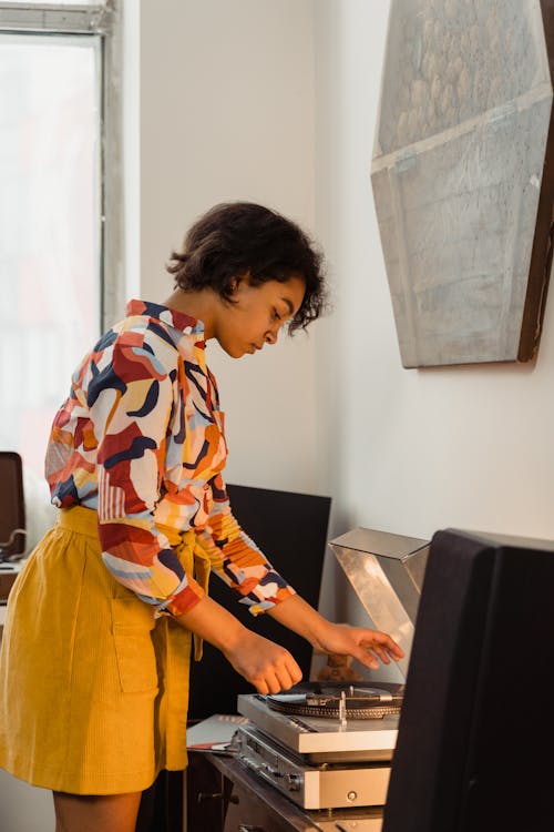 A Woman Playing Vinyl Records on a Turntable