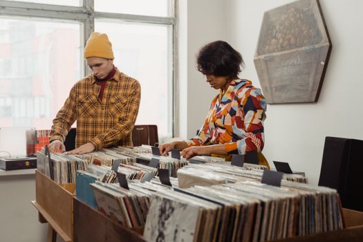 Two people browsing vinyl records in a retro-style store, indoors with vintage decor.