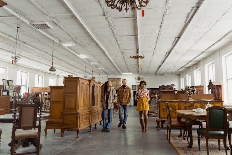 Two Women And Man Walking In Pavilion With Vintage Furniture