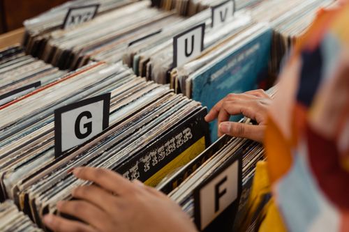 Free Person searching through labeled vinyl records in a store, capturing the essence of nostalgia and music. Stock Photo