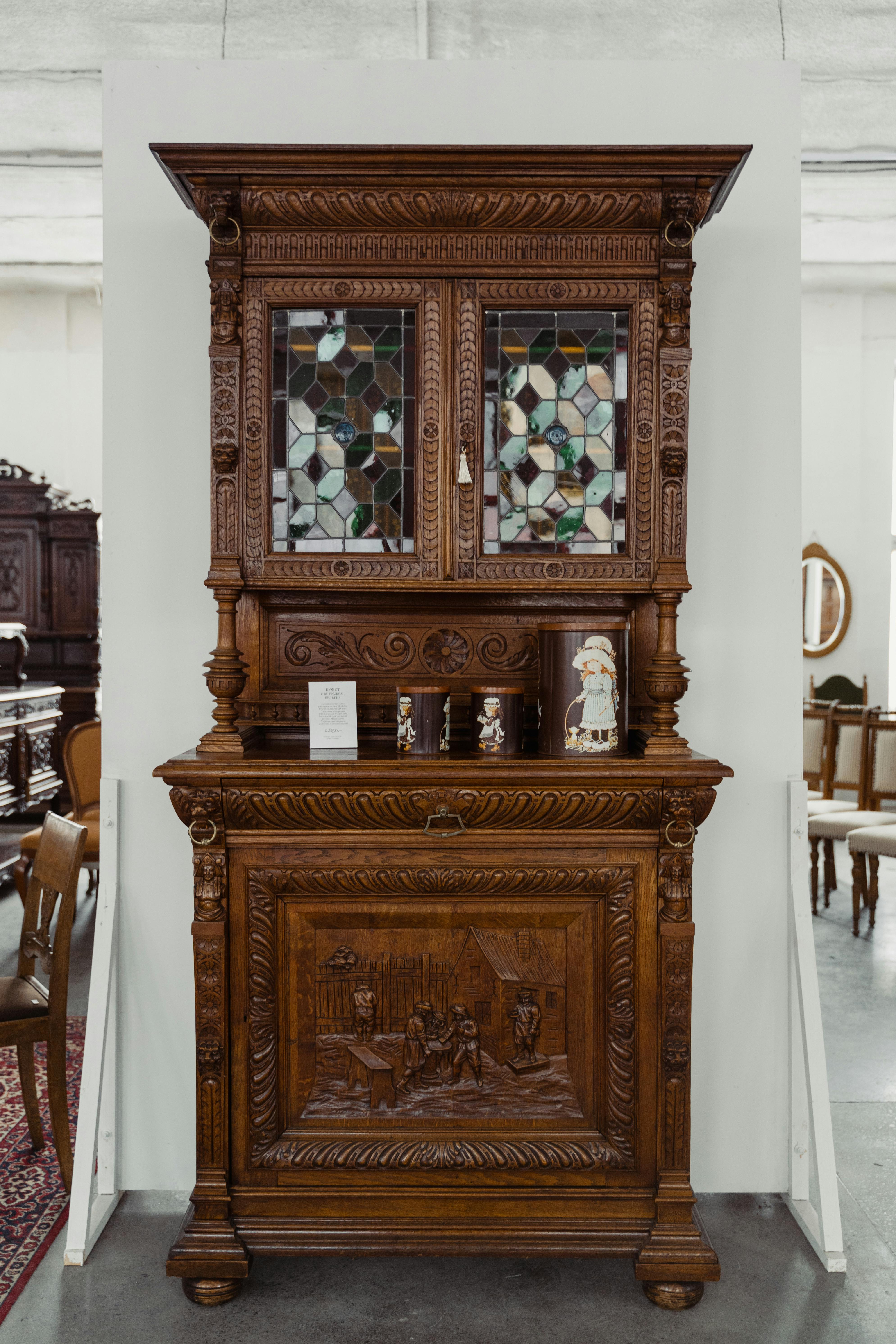 Vintage wooden cabinet with detailed carvings and stained glass doors on display.