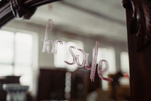 Close-up of vintage mirror with 'For Sale' message written in lipstick. Ideal for marketing and sales concepts.