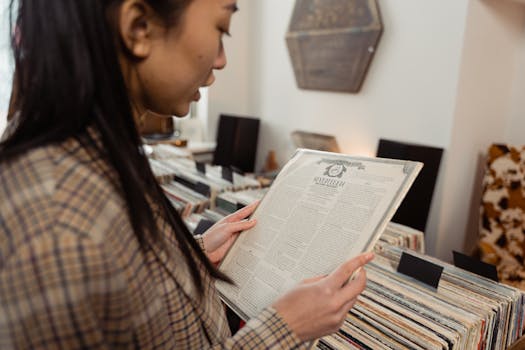 A woman in plaid jacket examines vinyl records in a music store.