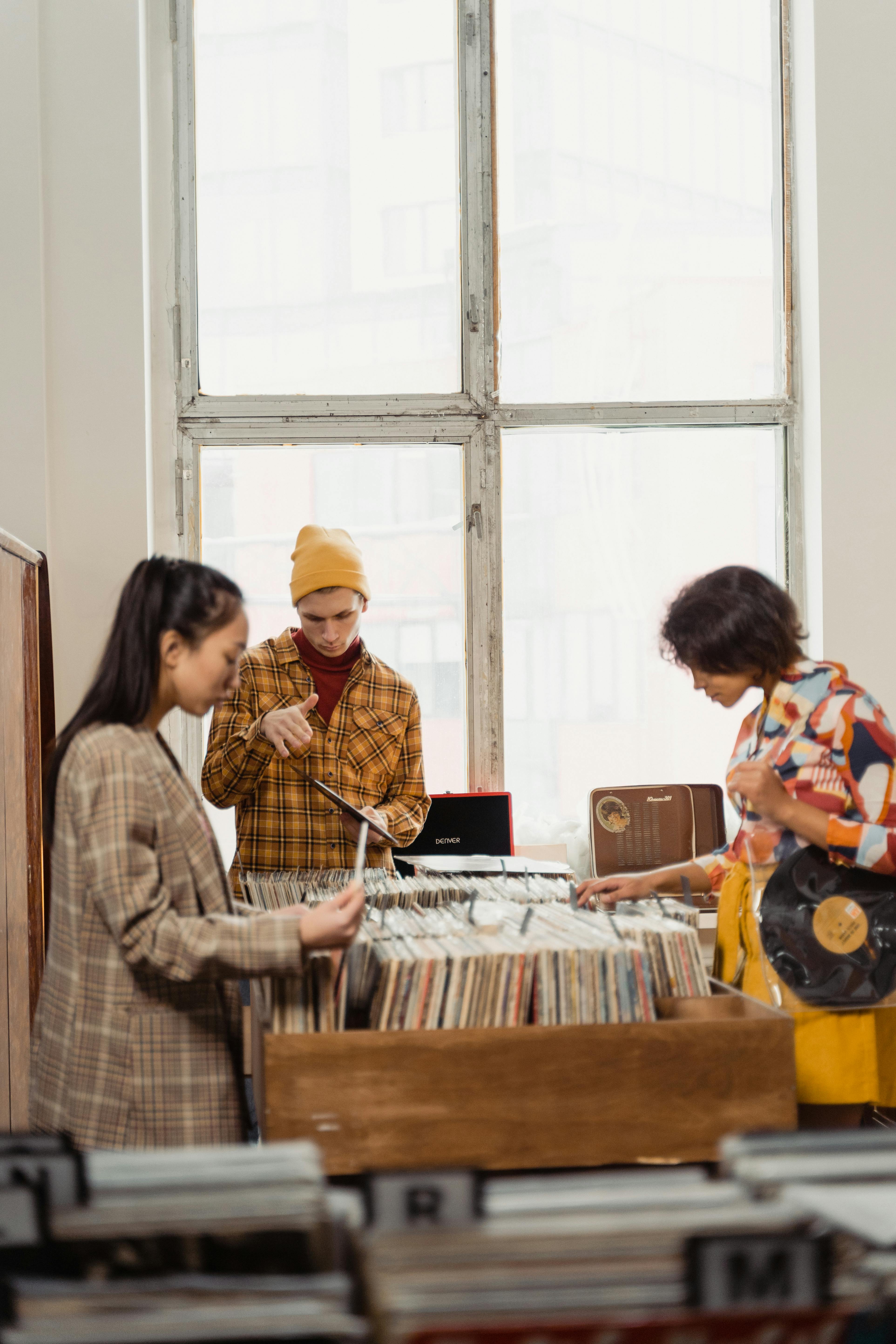 two women and man choosing vinyl record in vintage store