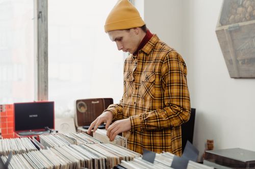 Free A young man in a beanie explores a vinyl collection in a vintage-style record store. Stock Photo