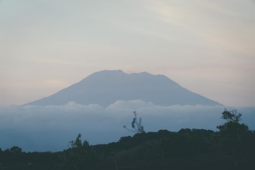 Free Beautiful misty mountain peak rising through clouds at dawn, creating a tranquil landscape. Stock Photo
