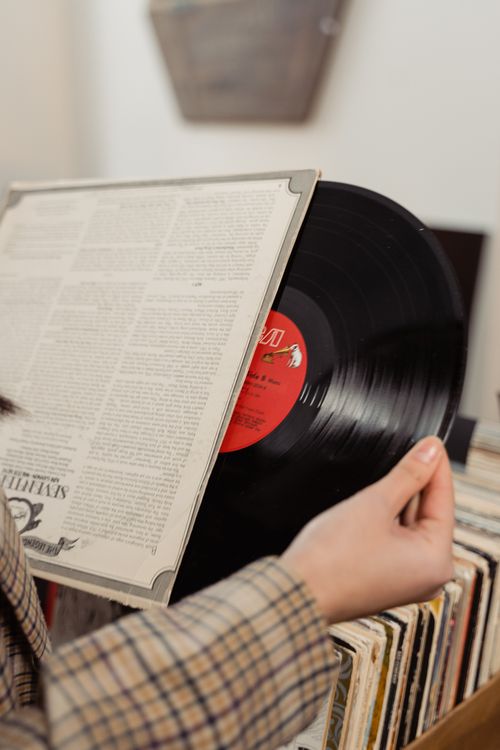 Free A person holding a classic vinyl record, browsing through a collection in a vintage music store. Stock Photo