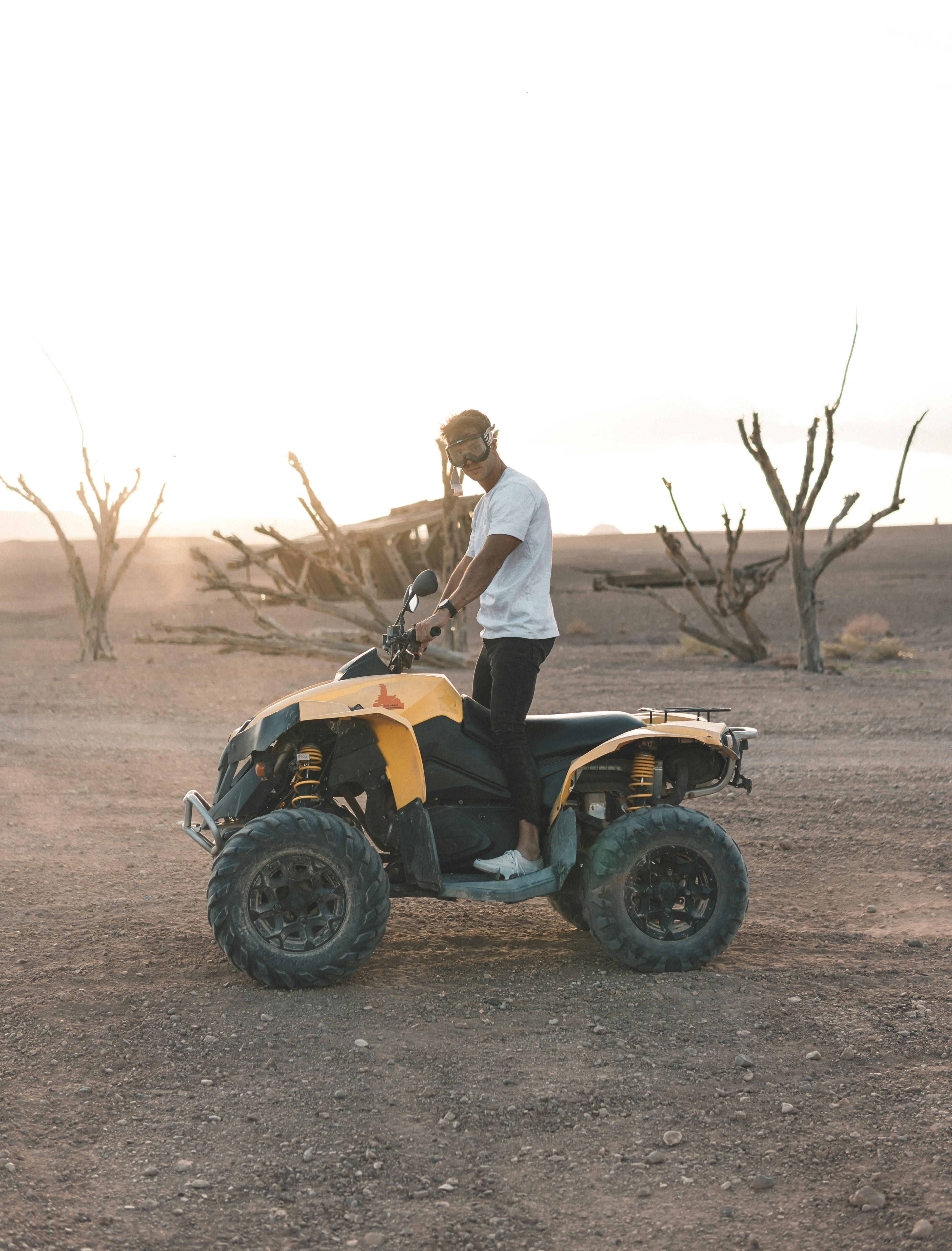 A person riding an ATV across a dusty desert landscape during sunset, capturing the thrill of adventure.