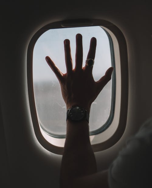 A Passenger Hand on the Airplane Window