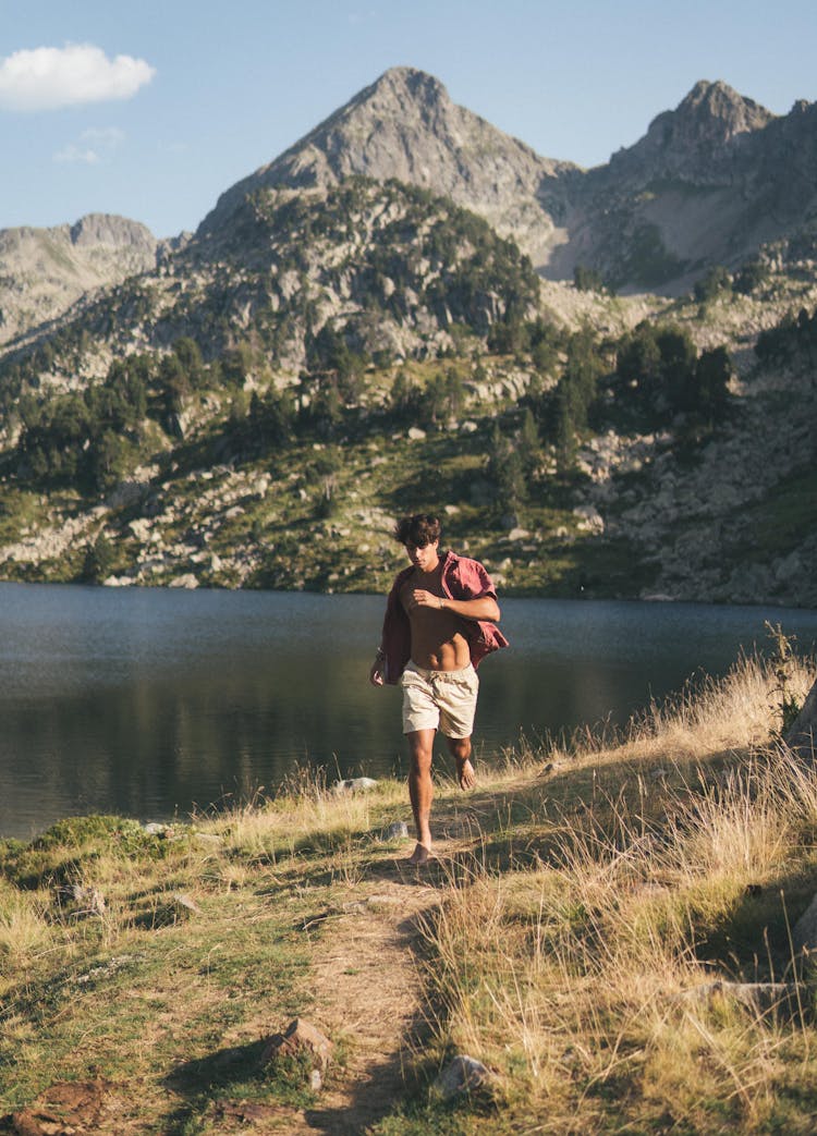 Young Shirtless Man Running On A Field In A Mountain Valley 