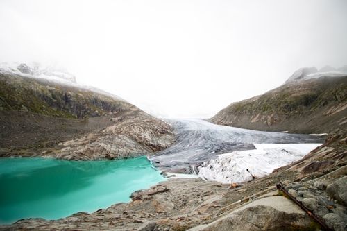 Free Breathtaking view of a glacier merging into a turquoise lake, surrounded by rugged mountains in Obergoms, Switzerland. Stock Photo