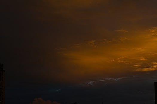 A dramatic twilight sky with dark clouds and golden hues over a cityscape.