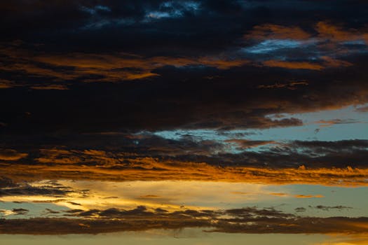 A breathtaking view of dark clouds with warm hues during sunset.