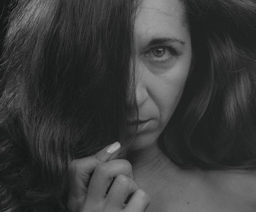 Free Intimate grayscale portrait of a woman partially covering her face with hair. Stock Photo