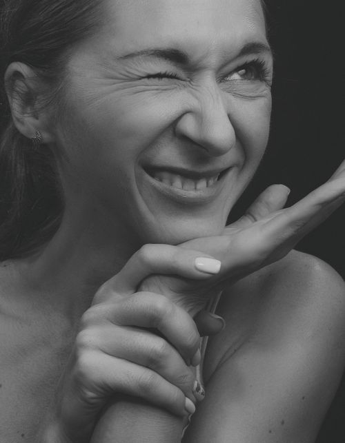 Free Close-up black and white portrait of a woman smiling with hand on chin, exuding happiness. Stock Photo