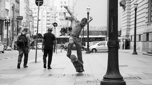 Free Energetic skateboarder performing tricks on a bustling street in São Paulo, Brazil. Stock Photo