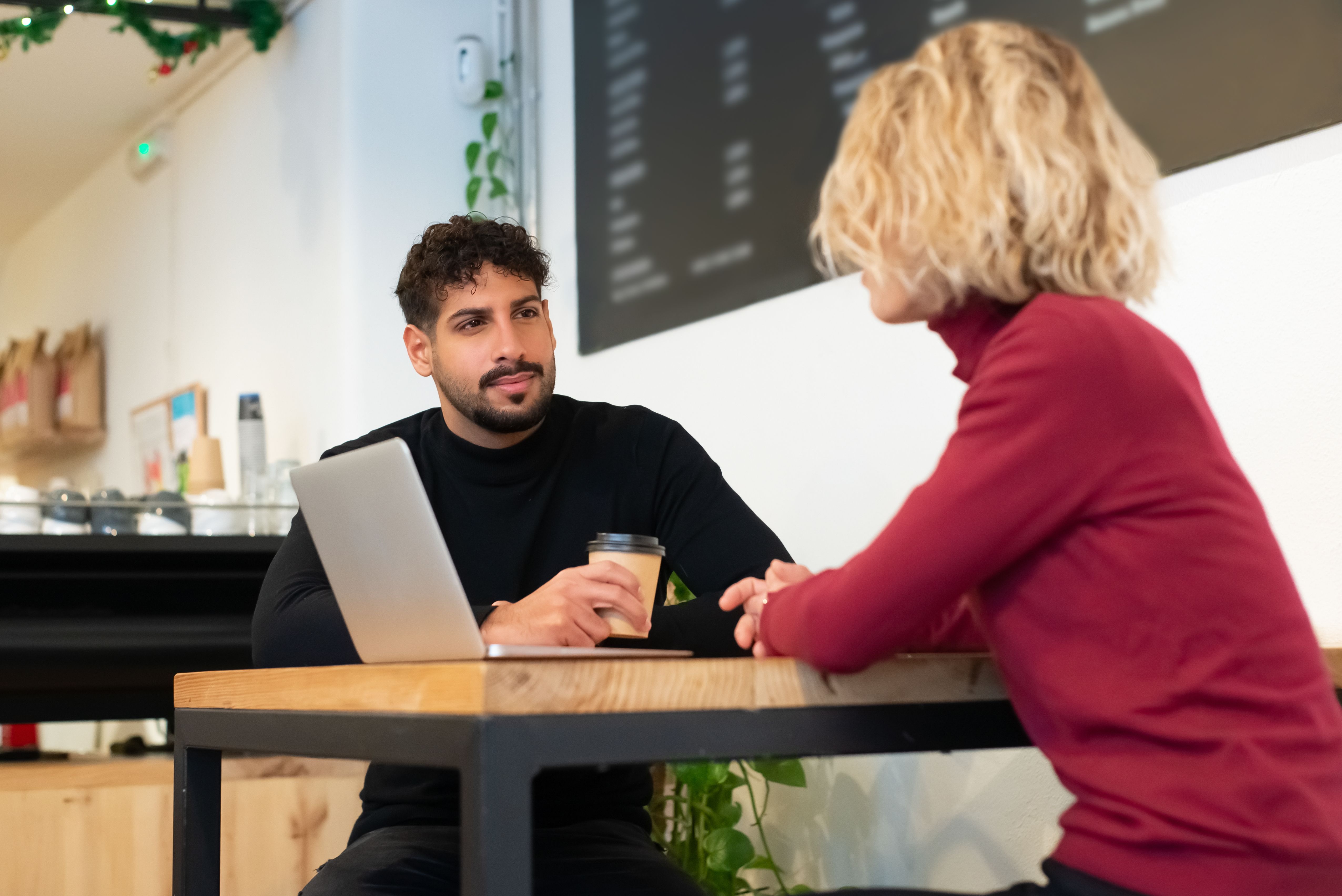 Deux personnes en pleine conversation autour d'un café dans un lieu moderne