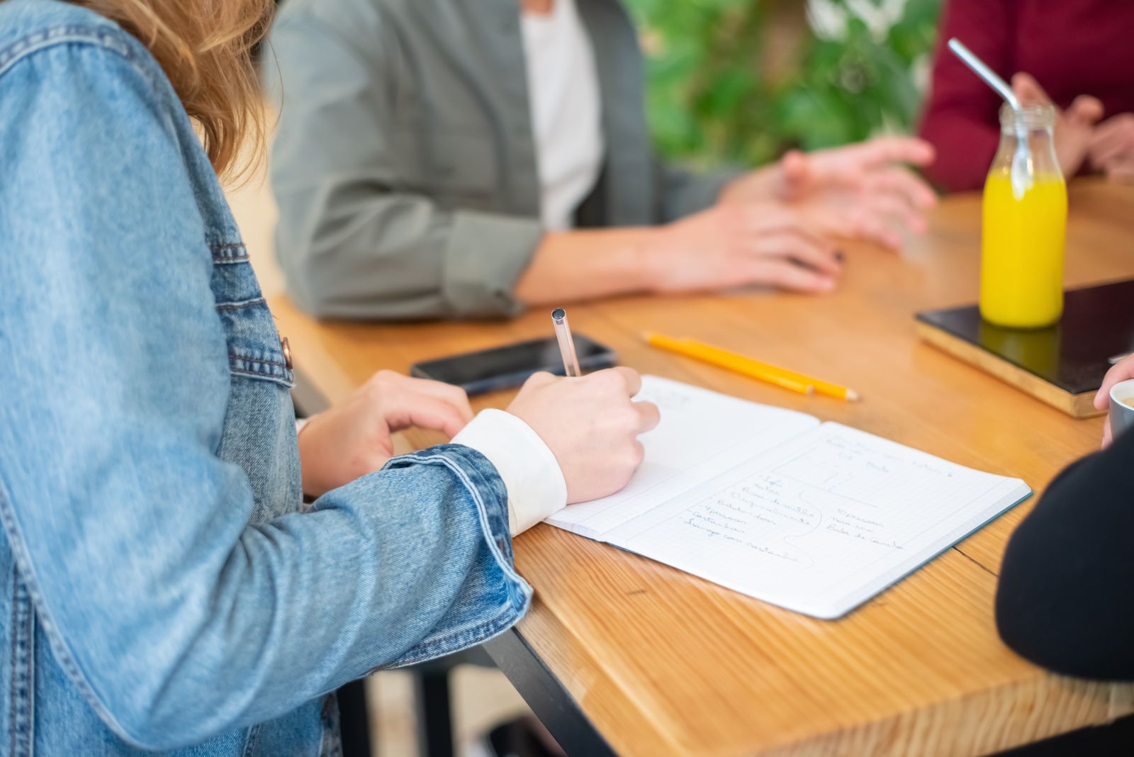 People discussing ideas while taking notes around a table