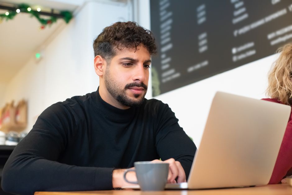 A man working on his laptop in a cozy cafe, embodying modern remote work culture.