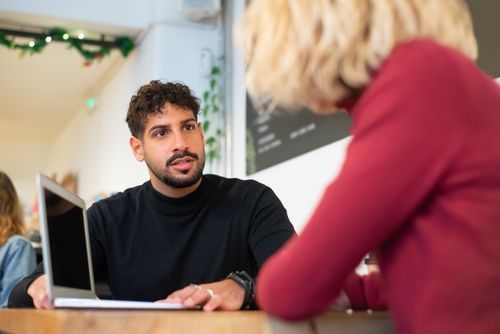 Free Business discussion at a café table, focusing on collaboration using a laptop. Stock Photo