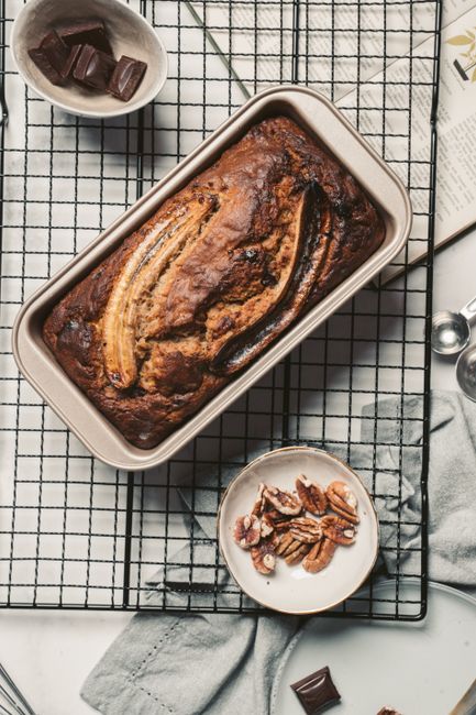 Delicious homemade banana bread with nuts and chocolate on a cooling rack.