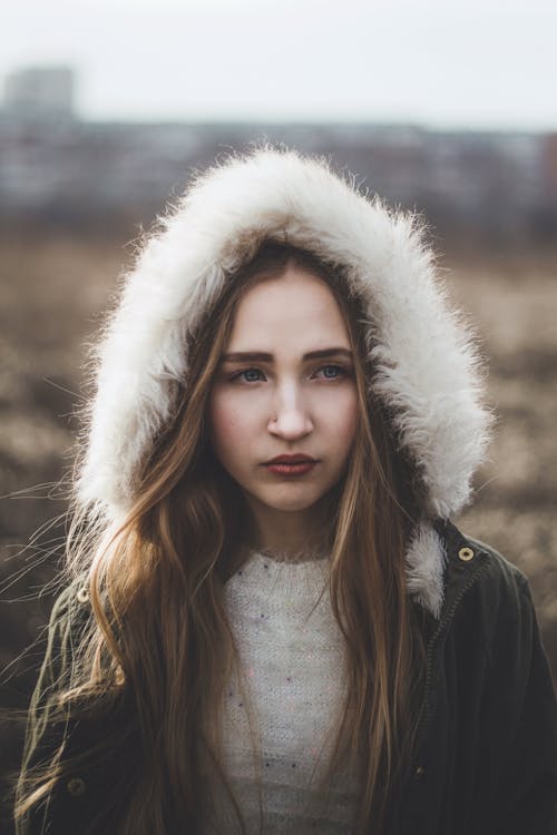 Young pensive woman in warm hood with fur