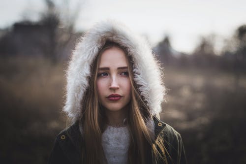 Lonely woman in warm jacket standing in autumn countryside