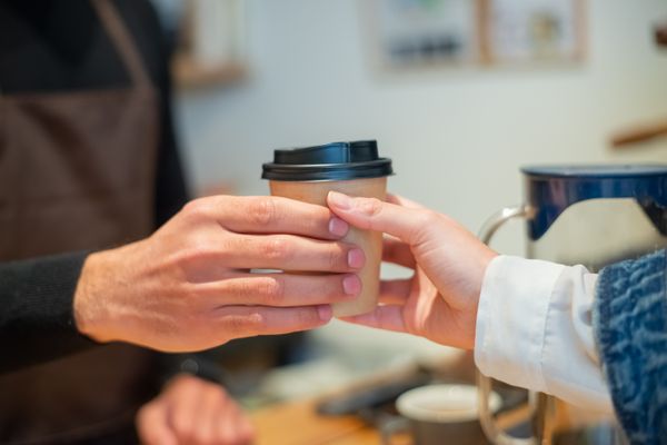 Barista handing a coffee cup to a customer