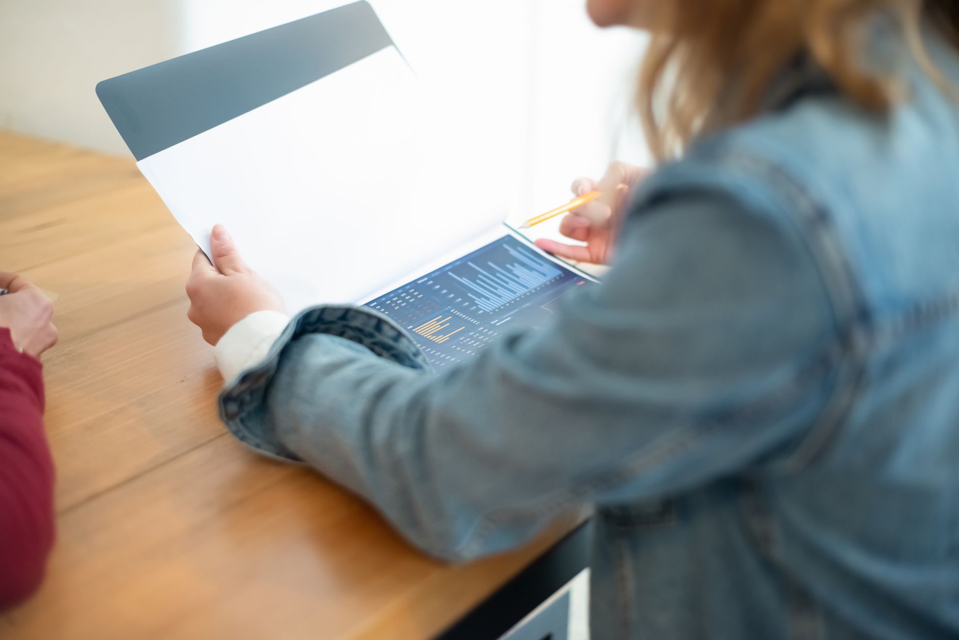 Business meeting discussion with focus on data charts and documents on a desk.
