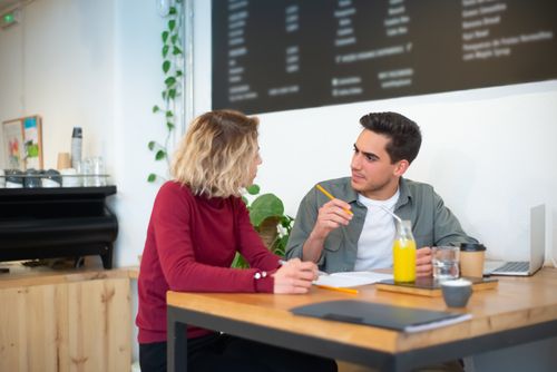 Free Two coworkers discussing projects over coffee and juice in a vibrant café. Stock Photo