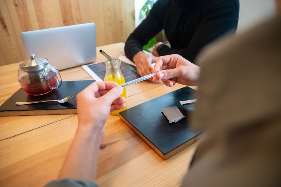Reunión de negocios informal con bebidas y discusión en un ambiente de café acogedor.