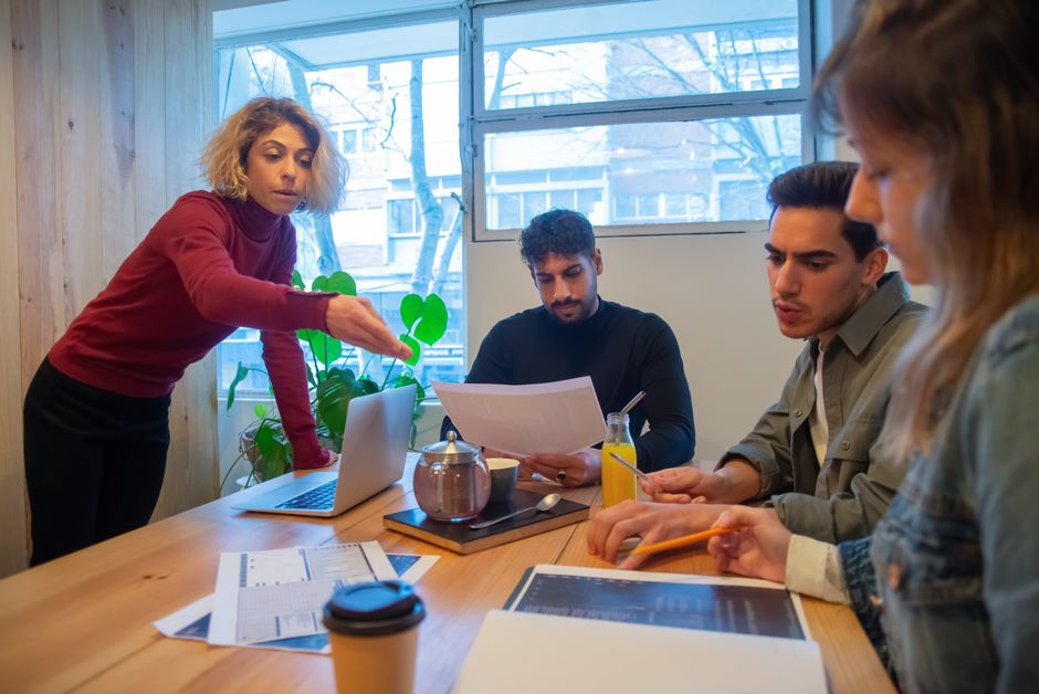 Profesionales colaborando en un entorno de oficina moderno con laptops y documentos.