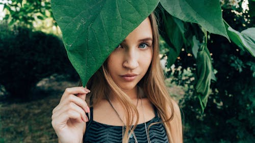 Woman with piercing touching fresh green leaf