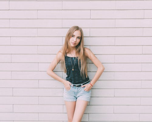 Young female with long fair hair looking at camera near wall of modern building