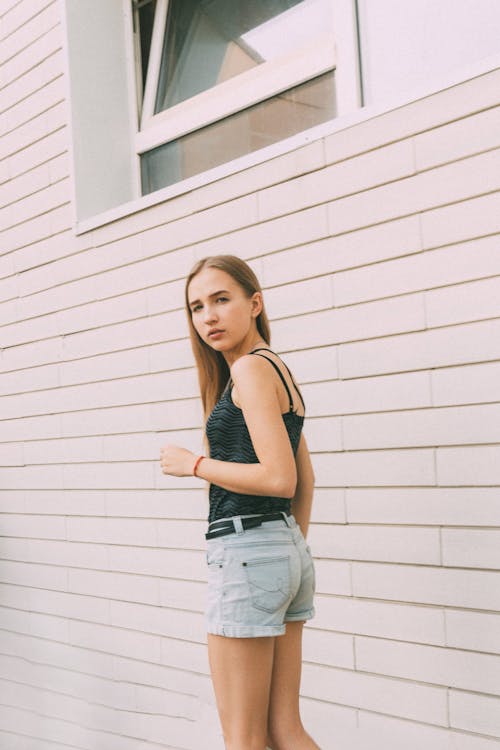 Young woman in denim shorts near modern building