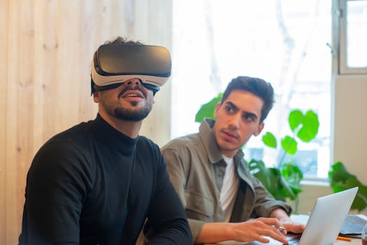 Two adult men engaged with virtual reality and laptop technology in a contemporary office.