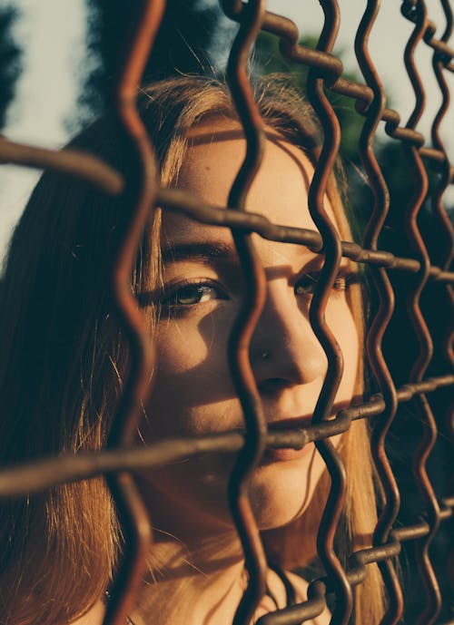 Woman looking through metal chain link on street