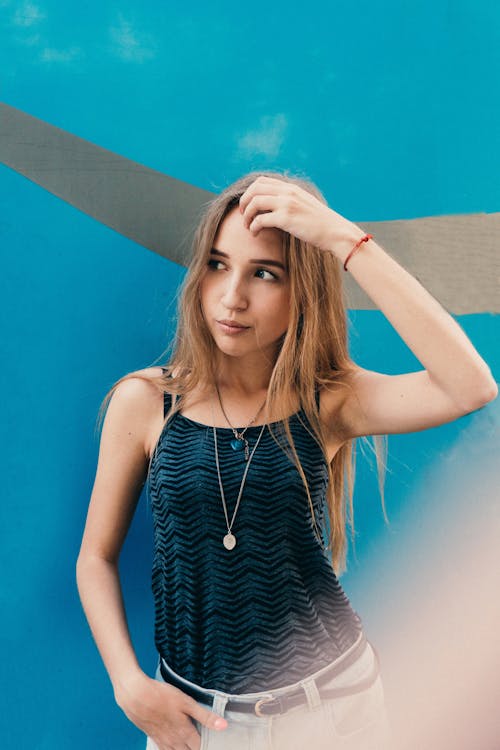 Young female with long fair hair touching head and looking away on creative background