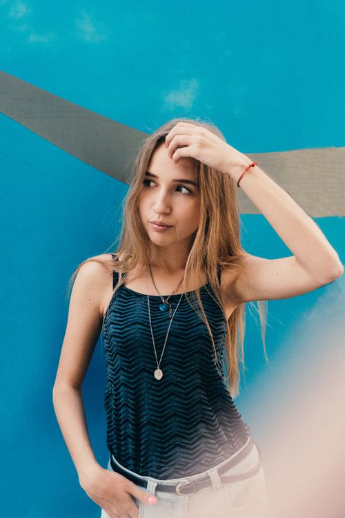 Free Young female with long fair hair touching head and looking away on creative background Stock Photo
